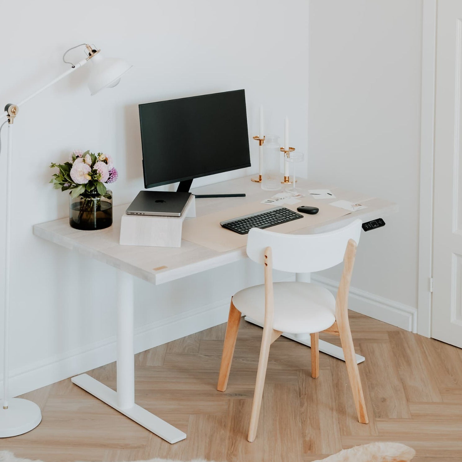 Modern home office with a desk, computer, and chair in a minimalistic room.