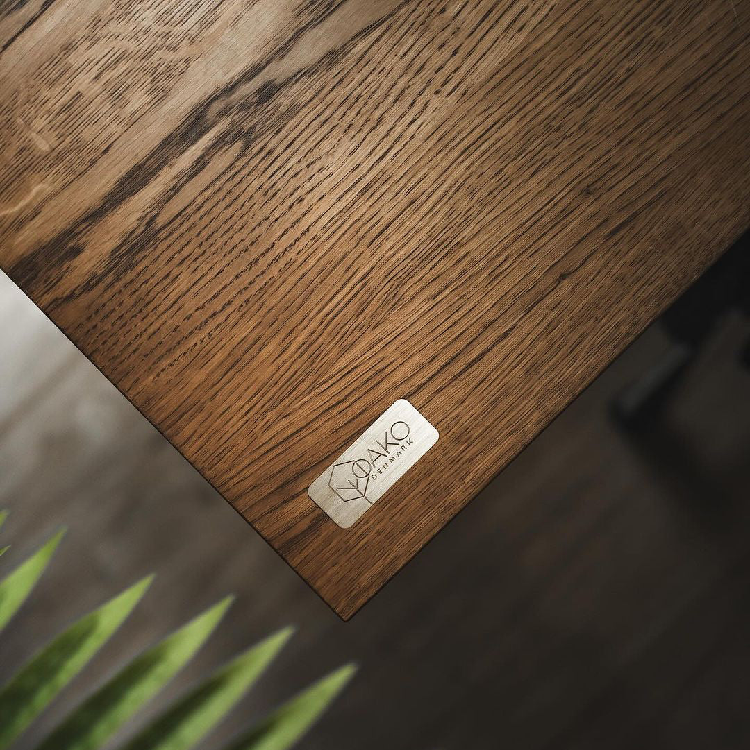 Wooden surface with a OAKO logo and a plant in the foreground