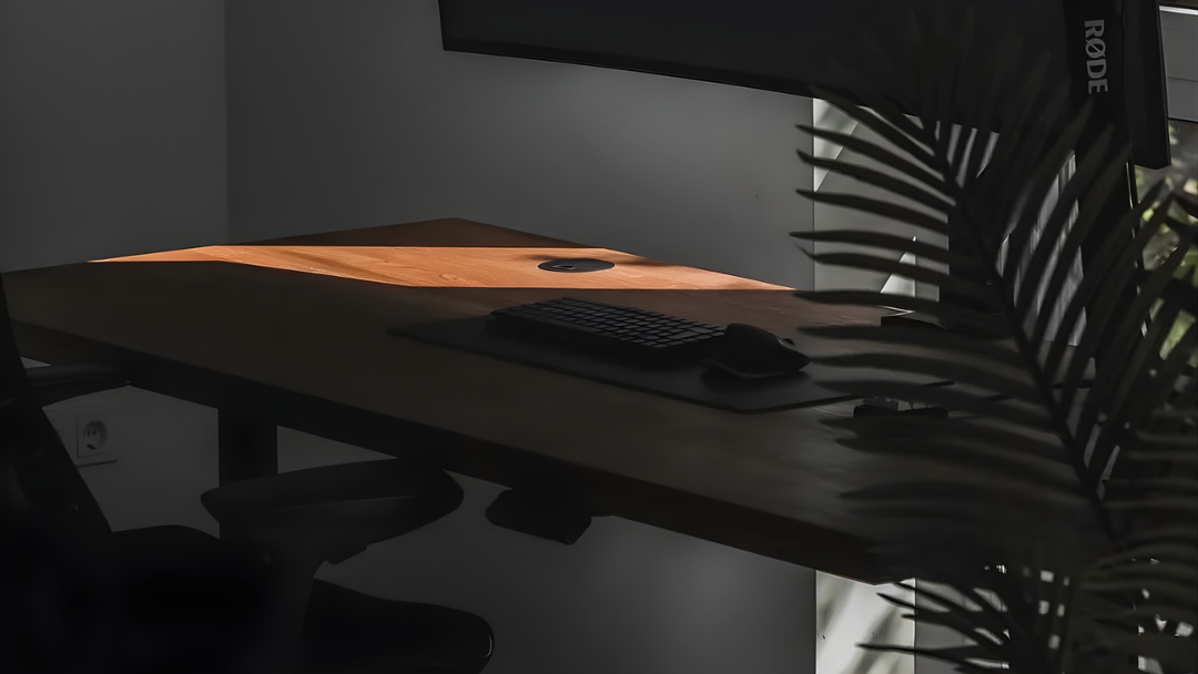Dark room with a desk setup featuring a computer monitor, microphone, and chair.